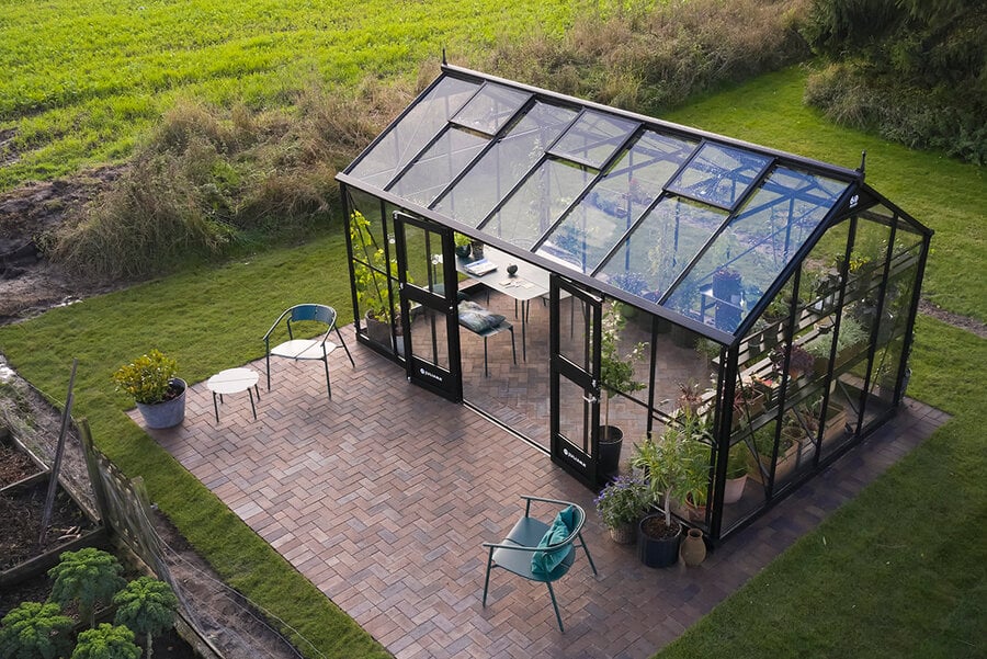 Juliana Jubii – L-förmiges Gewächshaus auf Backsteinpflaster